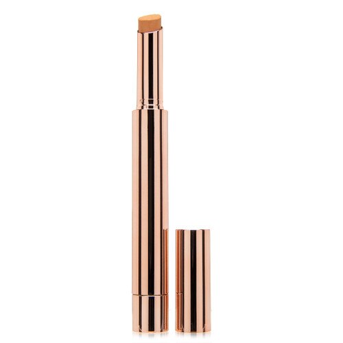 A tall thin rose gold tube frosted with the Kandi Koated logo containing a Finesse concealer stick in Caramel, its cap sitting beside it on a white background.